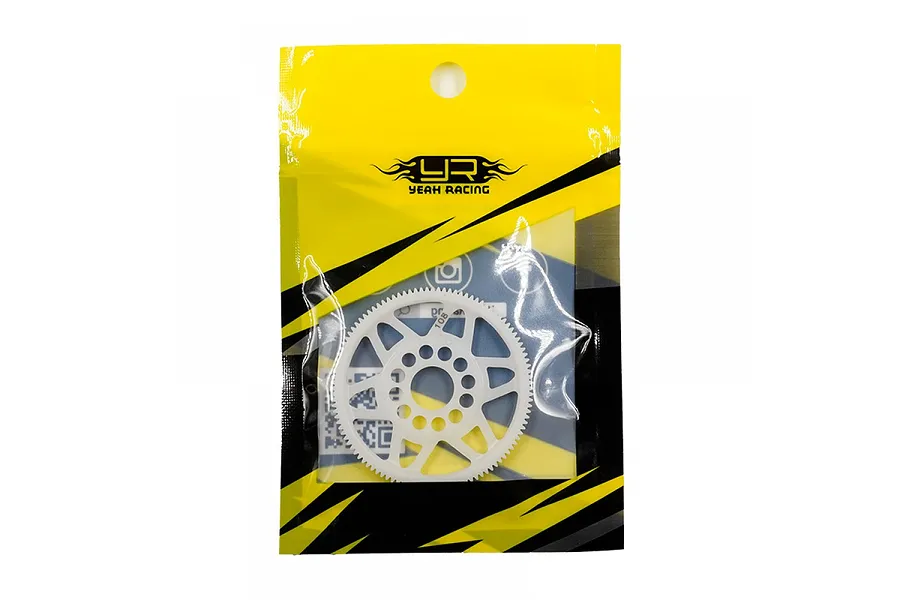 A white Delrin spur gear in its original Yeah Racing yellow and black plastic packaging.