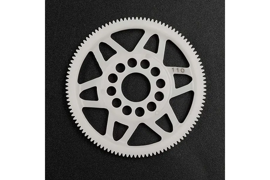 A white Delrin 110T 64dp spur gear for RC cars, featuring a spoked design and central mounting holes, set against a dark textured background.