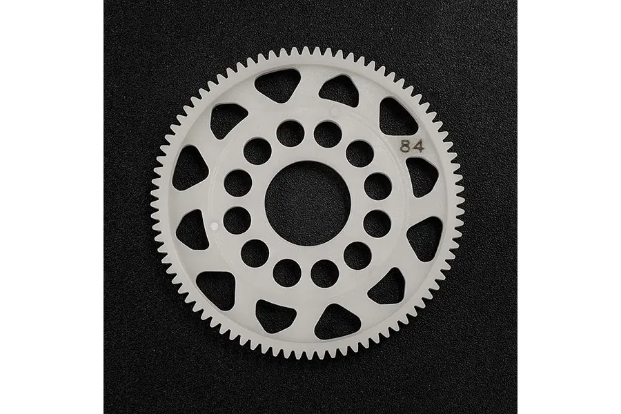 A white Delrin 84T spur gear for RC cars, featuring a circular design with multiple cutouts and the number 84 printed on the surface.