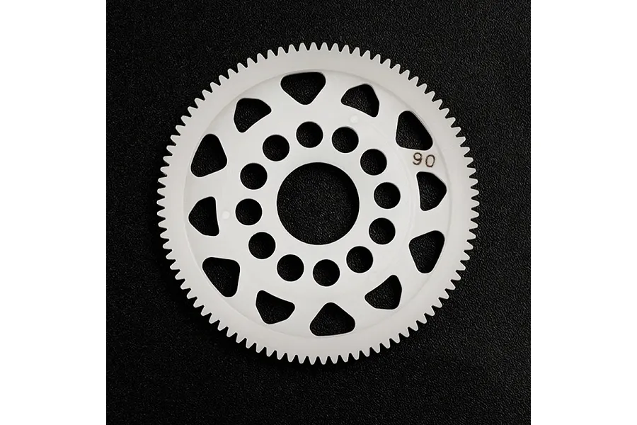 A white Delrin 90T spur gear for RC cars, featuring a circular design with weight-reduction holes, set against a black textured background.