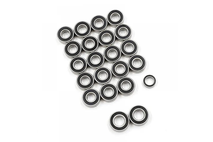 A collection of small metal ball bearings with black rubber seals arranged on a white background.