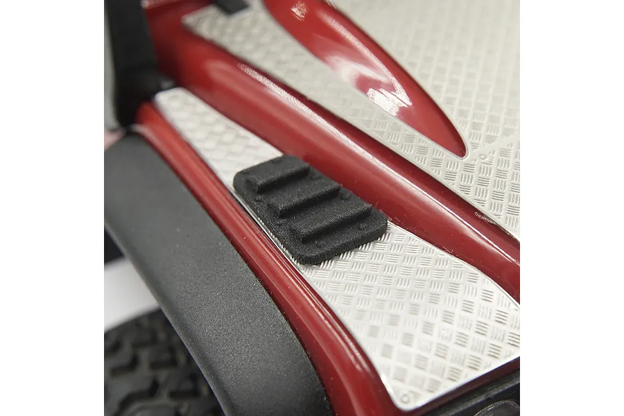 Close-up of a black plastic hood vent installed on a red RC car body with silver diamond plate detailing.