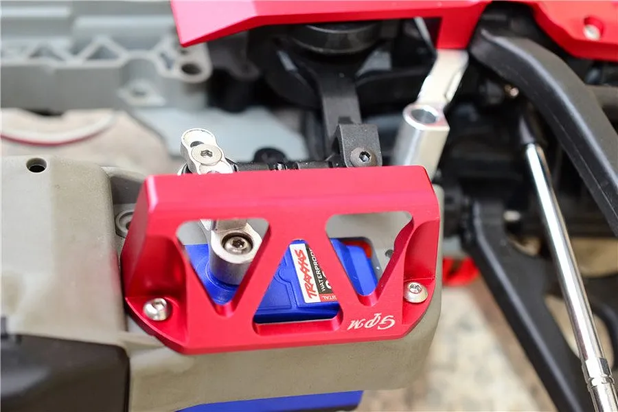 A red GPM Racing aluminium servo protector installed over a blue Traxxas servo on an RC car chassis.