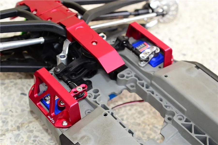Close-up of a red anodized aluminium GPM servo protector installed on an RC car chassis.
