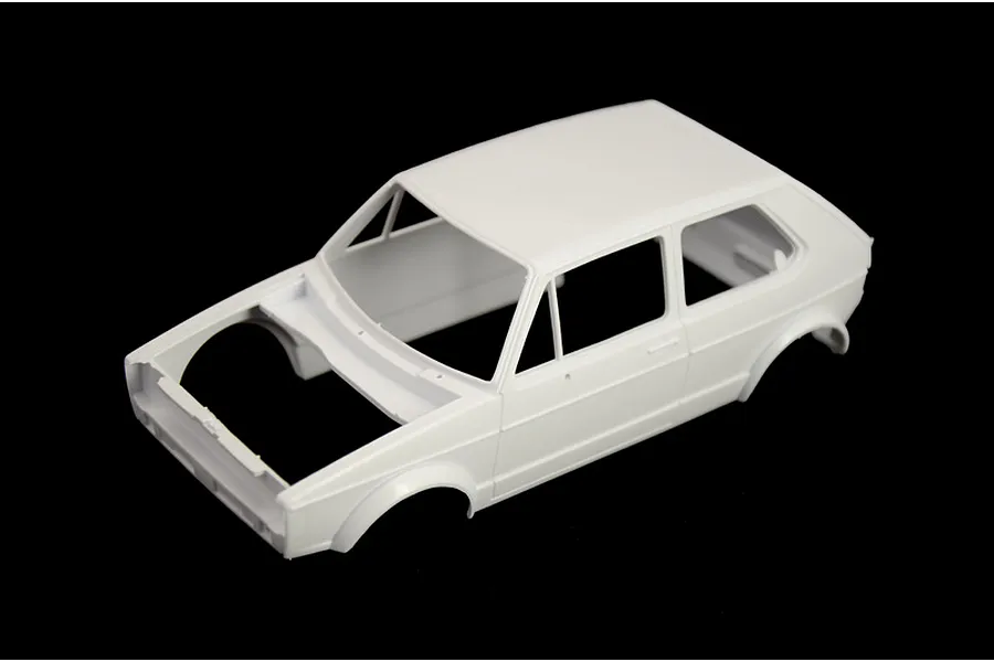 An unpainted white plastic model car body shell of a Volkswagen Golf, viewed from a high angle against a black background.