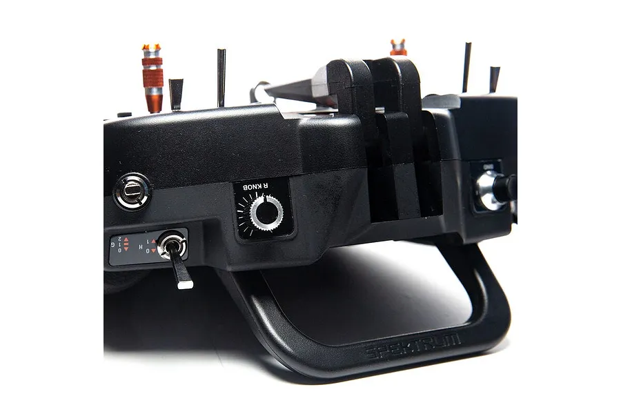 Close-up of the top section of a black Spektrum NX8 RC transmitter showing switches, a knob, and the carry handle.