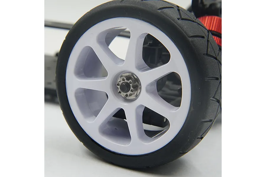A close-up of an RC car wheel with a silver flanged serrated nut installed on the axle.