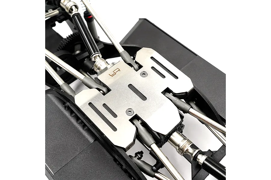 A stainless steel skid plate installed on the underside of an RC crawler chassis, featuring the Yeah Racing logo.