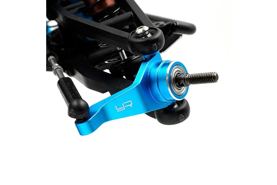 A blue anodized aluminium RC steering hub installed on a black suspension arm assembly.
