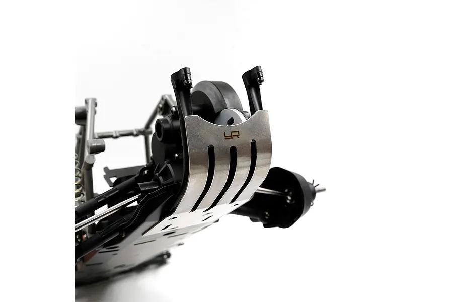 A stainless steel skid plate with the Yeah Racing logo installed on the front of an RC vehicle chassis.