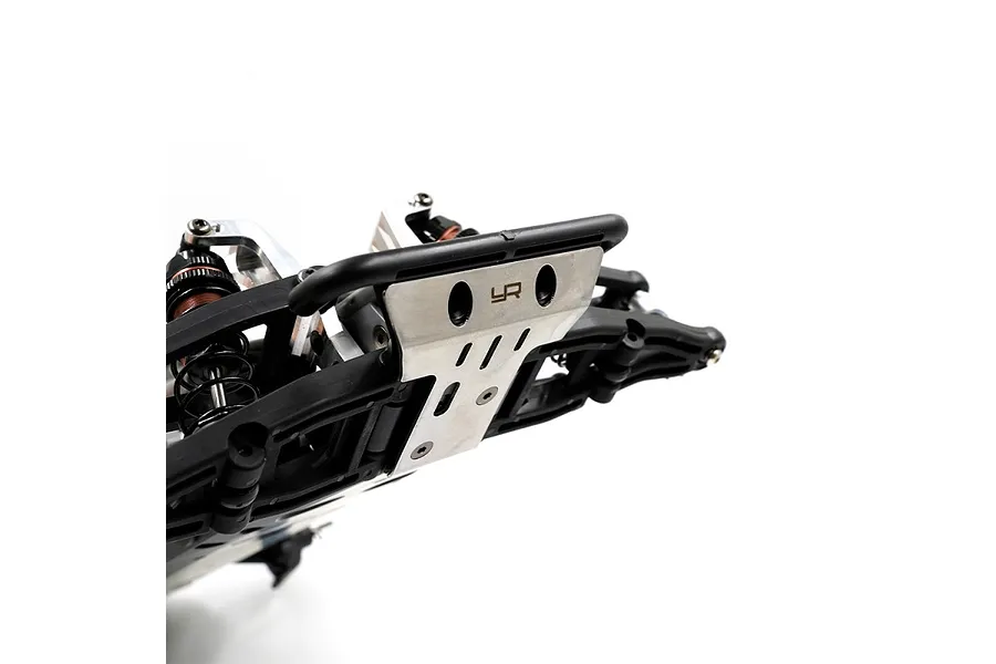 A close-up view of a stainless steel skid plate installed on the front of an RC vehicle chassis, featuring the Yeah Racing logo.