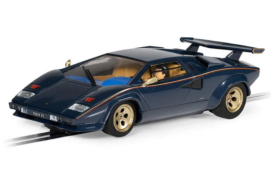 A 1/32 scale Scalextric Lamborghini Countach slot car in dark blue with gold wheels, positioned on a section of slot car track.