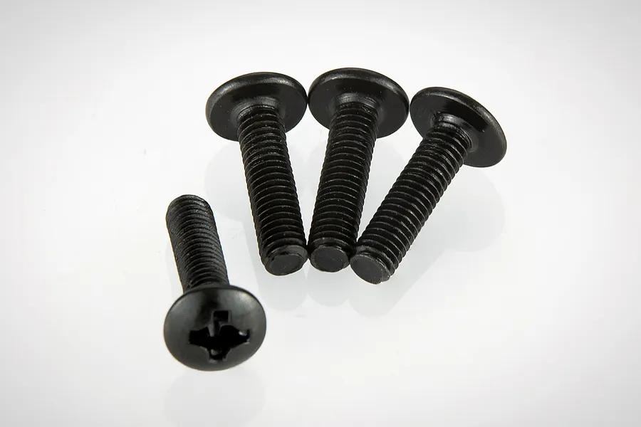 Four black metal button head screws with Phillips drive heads arranged on a white background.