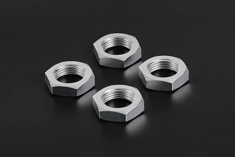 Four silver aluminium wheel nuts arranged in a diamond pattern on a dark background.