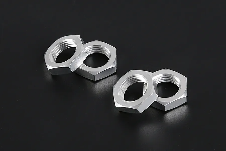 Four silver-coloured aluminium hex wheel nuts arranged in two pairs on a dark background.