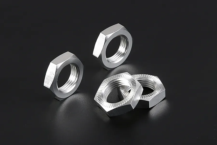 Four silver aluminium hex wheel nuts for RC vehicles arranged on a dark background.