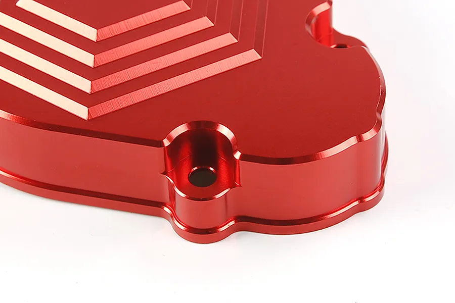 Close-up of a red anodized aluminium transmission case for an RC car, showing the machined stepped design and mounting holes.