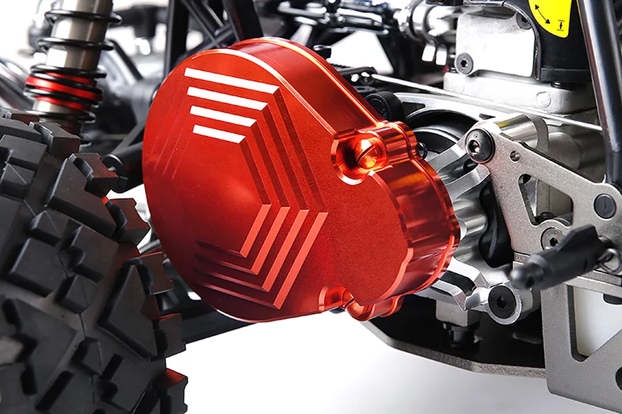 A close-up of a bright red anodized aluminium transmission case installed on an RC vehicle chassis.