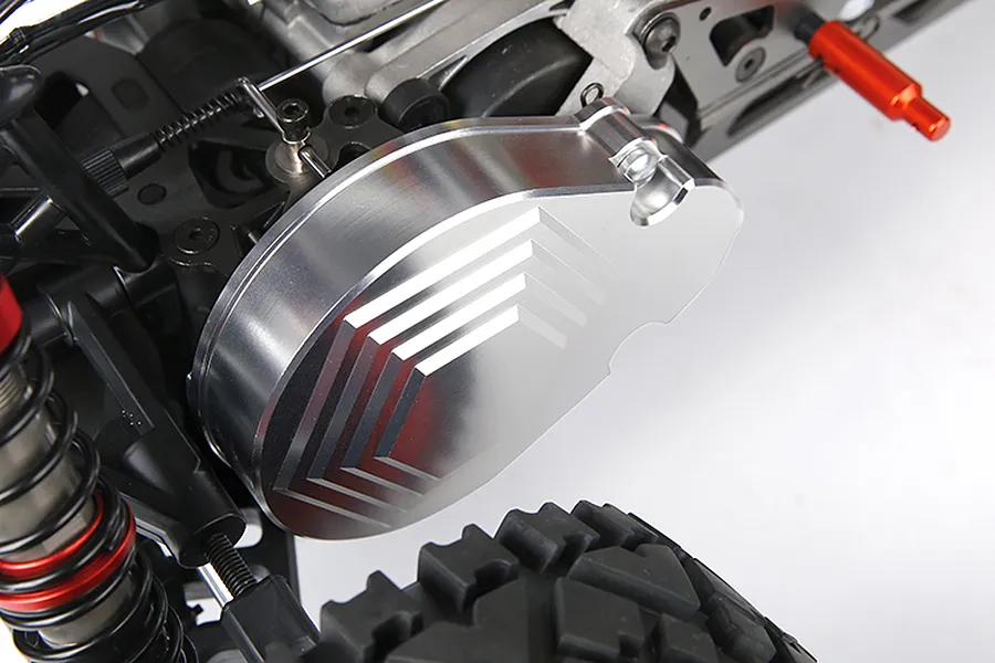 A silver aluminium transmission case installed on an RC car chassis, showing a machined chevron pattern on the cover.