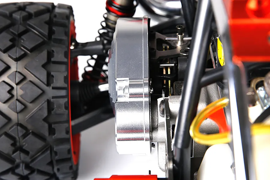 Close-up of a silver aluminium transmission case installed on an RC buggy chassis, showing the gear cover and surrounding suspension components.