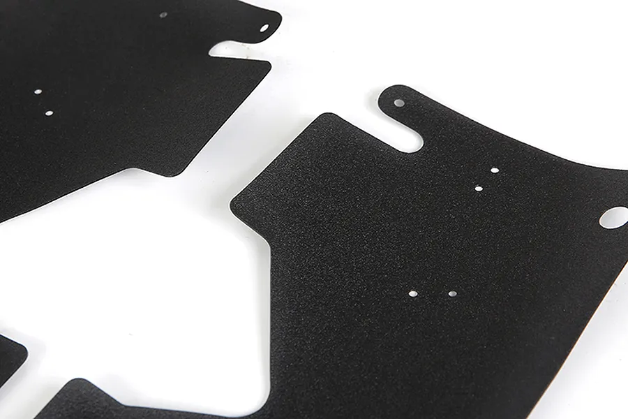 A close-up view of two black, textured RC dust guard panels with pre-drilled mounting holes against a white background.