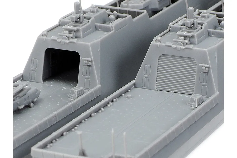 Close-up of two unpainted grey plastic model ship decks from the Tamiya 1/700 JMSDF FFM-1 Mogami kit, showing hangar doors and deck details.