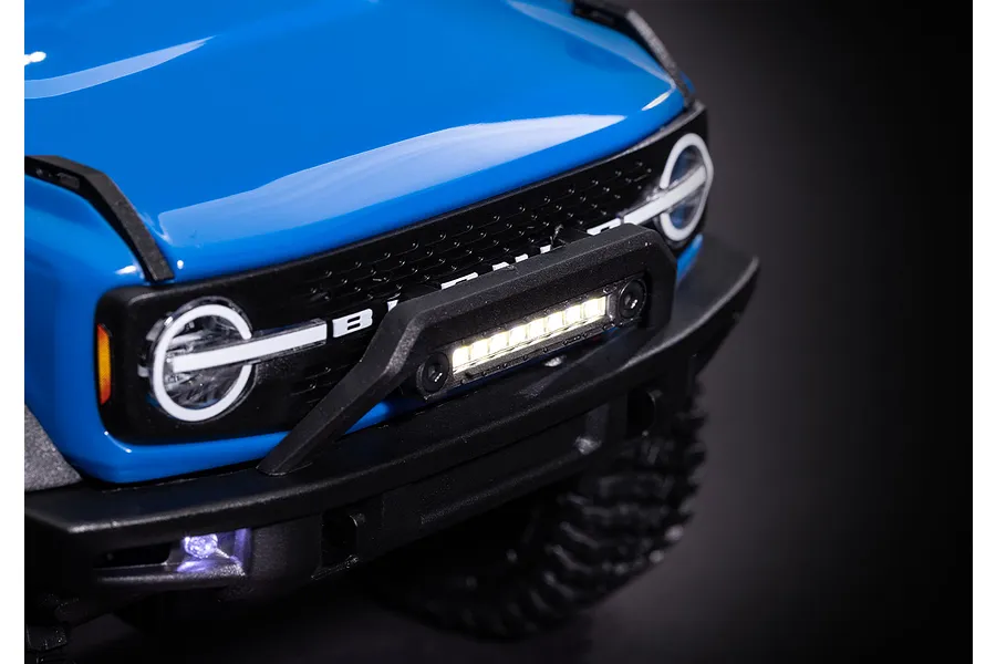 Close-up of a blue RC Ford Bronco front end featuring an illuminated LED light bar mounted on the front bumper.