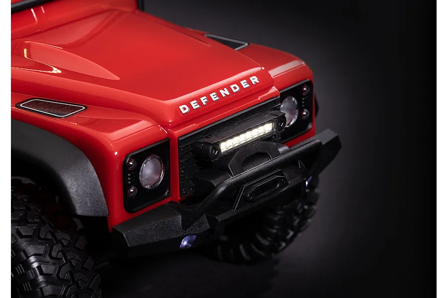 Close-up of a red RC Land Rover Defender front end featuring an illuminated LED light bar mounted on the grille.