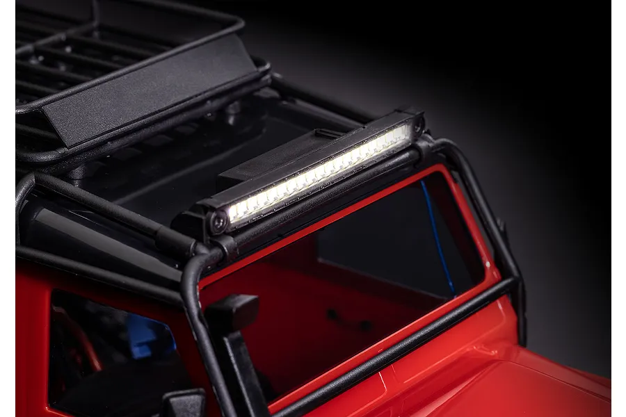 A bright LED light bar mounted on the roof rack of a red RC crawler vehicle, illuminated against a dark background.