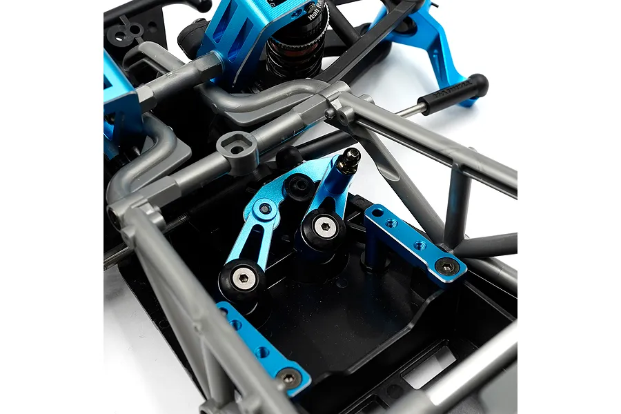 Close-up of a blue aluminium steering bellcrank and drag link set installed on an RC car chassis.