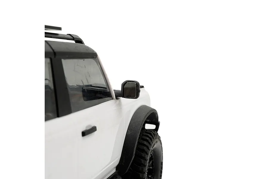 Close-up of a white RC off-road vehicle side mirror featuring a reflective mirror plate installed on the side housing.