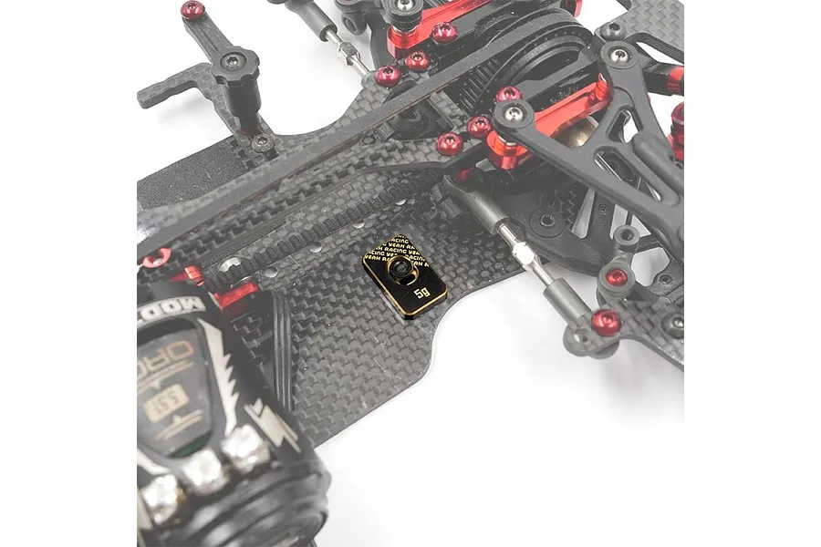 A 5g Yeah Racing brass balancing weight installed on a carbon fiber RC car chassis.