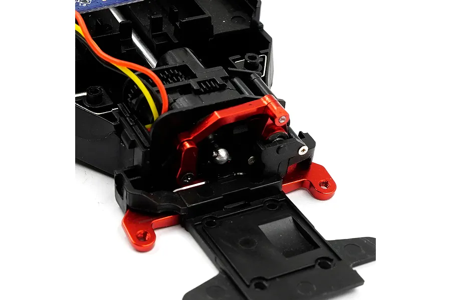A close-up view of a red aluminium servo saver component installed on a black plastic RC car chassis assembly.