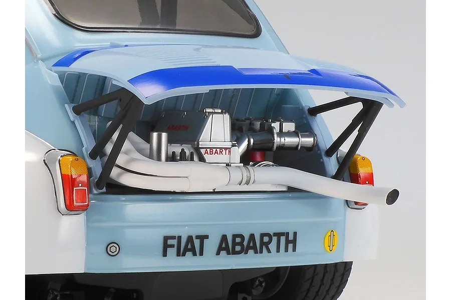 Close-up of the rear engine bay of a Tamiya Fiat Abarth 1000TCR RC car, showing the open engine cover, detailed engine block, and exhaust pipe.