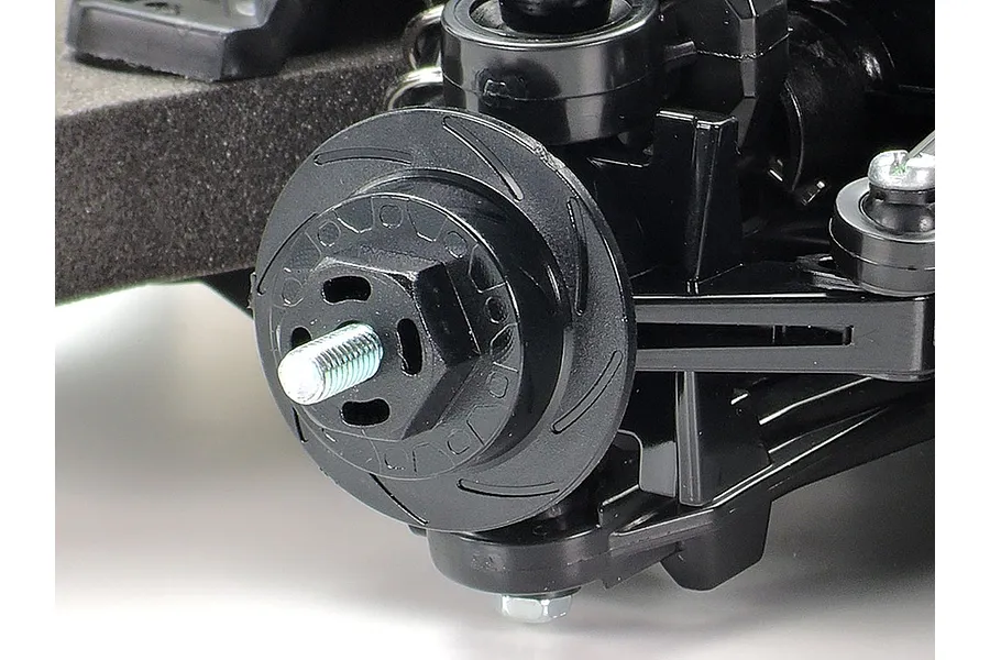 Close-up of a black plastic RC car wheel hub and suspension assembly on a Tamiya TT-02 chassis.