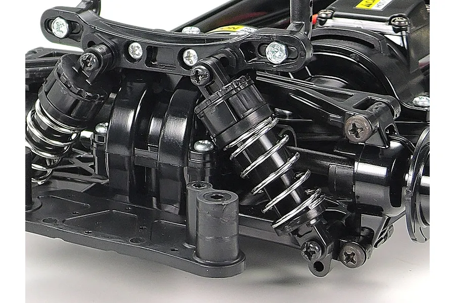 Close-up of the front suspension and shock absorbers on a Tamiya TT-02 RC car chassis.