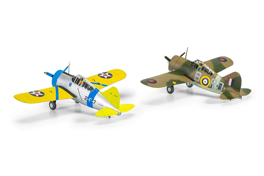 Two assembled and painted 1/72 scale Brewster Buffalo model aircraft on a white background, one in US Navy silver and yellow and one in RAF camouflage.