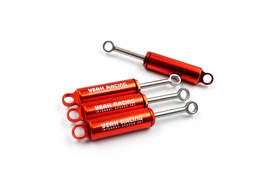 Four red anodized aluminium RC shock absorbers by Yeah Racing, featuring silver shafts and printed branding on the barrels.