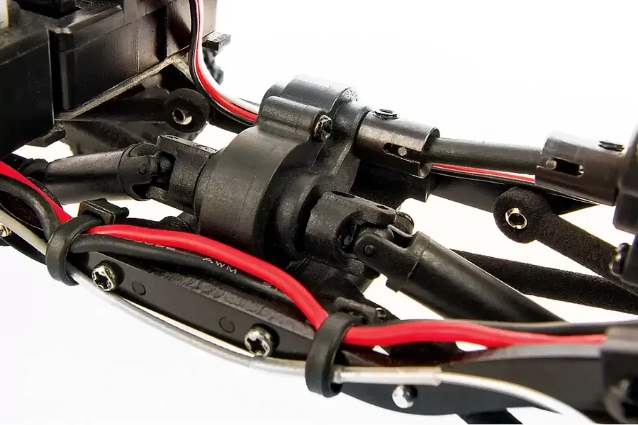 Close-up of the drivetrain and chassis components of an Element RC Enduro24 rock crawler, showing the central gearbox, driveshafts, and wiring.