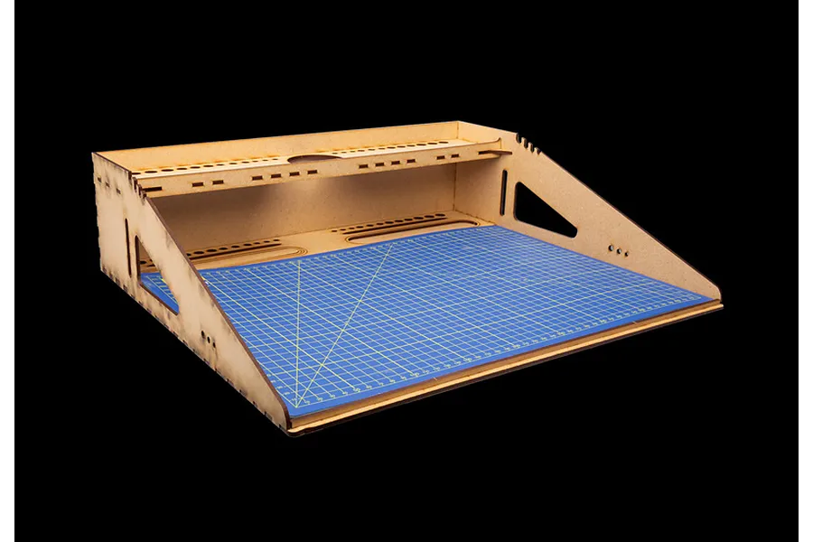 Italeri modelling workstation made of light wood with an A3 blue cutting mat featuring yellow grid lines.