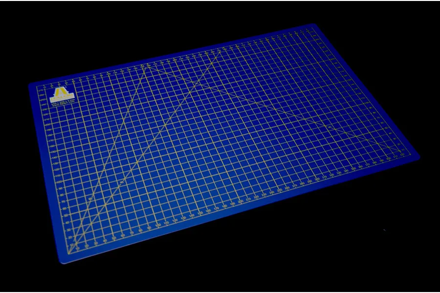 A blue Italeri A3 self-healing cutting mat with yellow grid lines and angle markings, isolated on a black background.