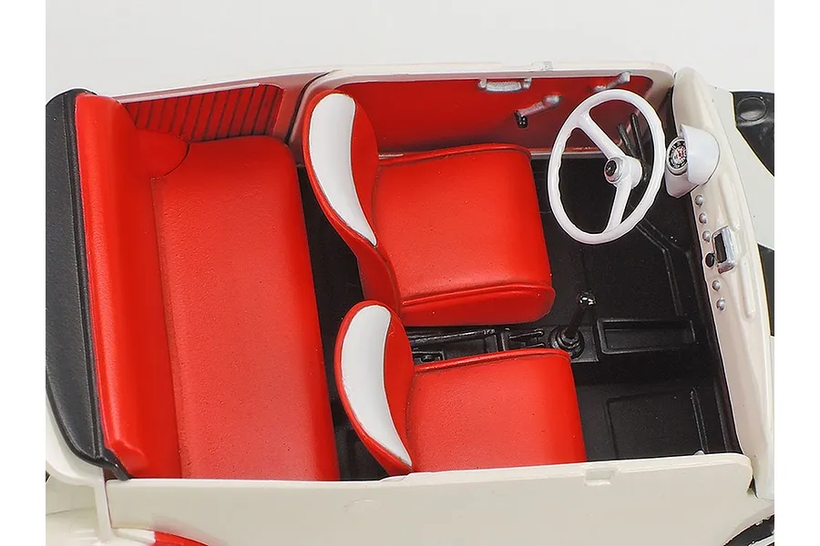 High-angle interior view of a Tamiya 1/24 scale Fiat 500F model car, showing red and white bucket seats, a white steering wheel, and a black floor.