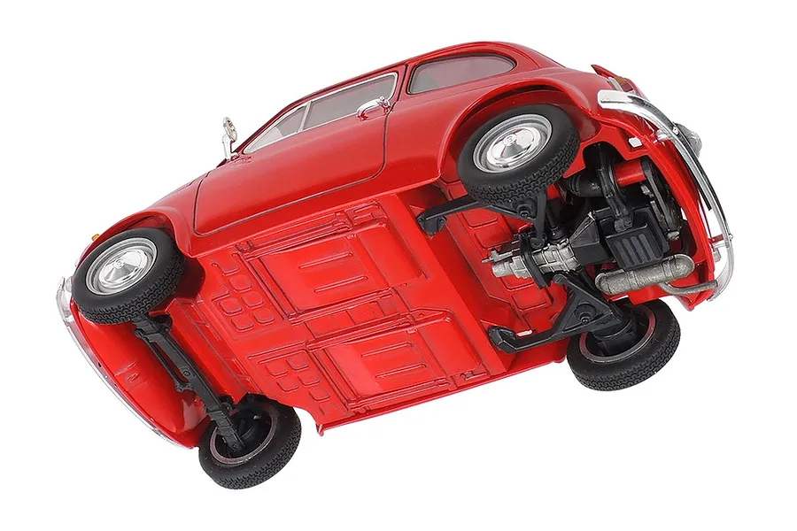 A low-angle view of a red Tamiya 1/24 scale Fiat 500F plastic model car, showing the detailed chassis, suspension, and undercarriage.