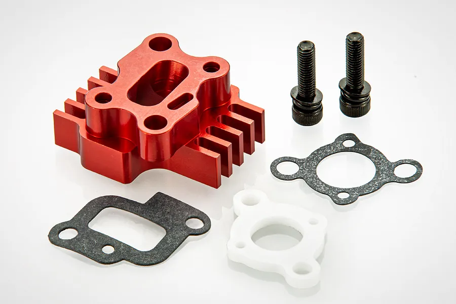 A red anodized aluminium air intake manifold with heat sink fins, two black bolts, and two gaskets on a white background.