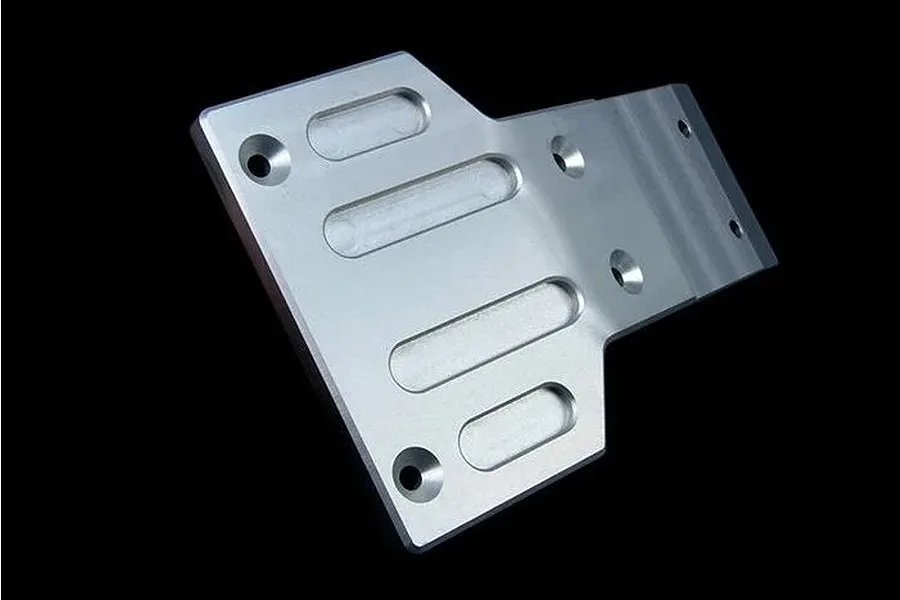 A silver aluminium front skid plate for an RC car, featuring machined slots and countersunk mounting holes, isolated against a black background.