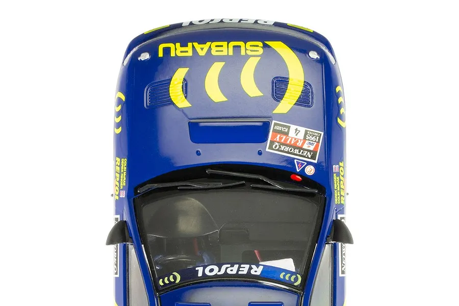 Top-down view of a blue Scalextric 1/32 scale Subaru Impreza WRX slot car featuring yellow rally decals and Colin McRae branding.