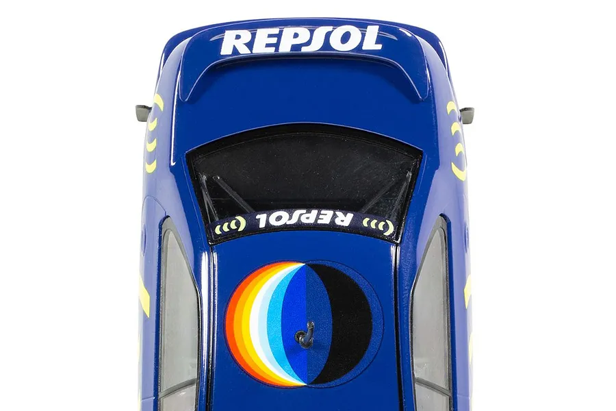 Top-down view of a blue Scalextric 1/32 scale Subaru Impreza slot car featuring Repsol branding and a circular rainbow graphic on the roof.