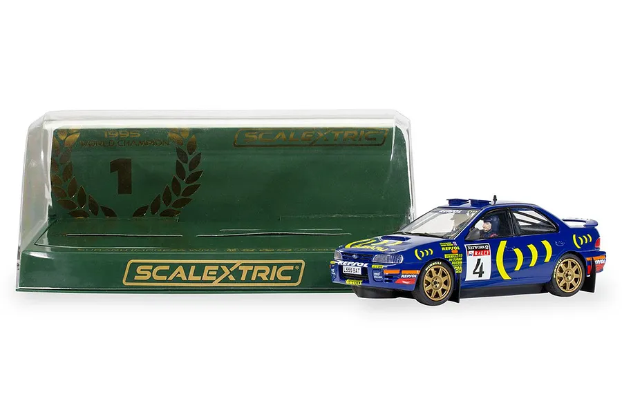 Scalextric 1/32 scale 1995 Subaru Impreza WRX slot car in blue with gold wheels, displayed next to its green branded display case.
