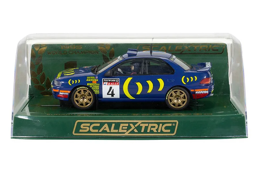 A 1/32 scale Scalextric Subaru Impreza WRX slot car in blue with gold wheels, displayed inside its original clear plastic and green cardboard packaging.