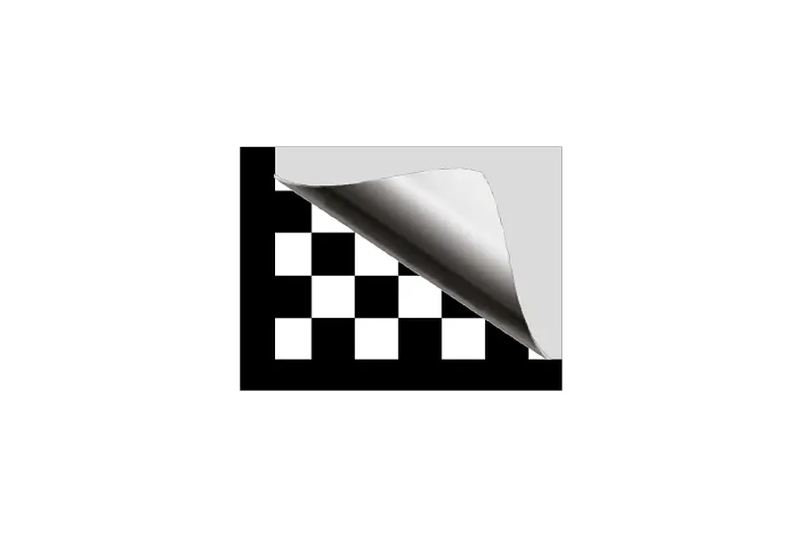 A sheet of black and white chequered pattern material with one corner peeled back to reveal a light grey backing.